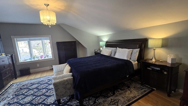 bedroom with lofted ceiling, a chandelier, and light hardwood / wood-style floors