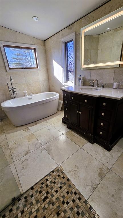 bathroom with tile walls, a bathtub, and vanity