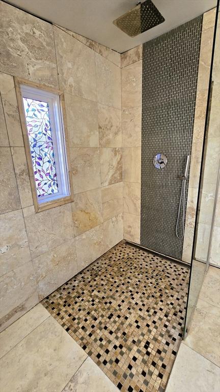 bathroom with tiled shower and tile patterned floors