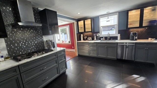 kitchen with decorative light fixtures, appliances with stainless steel finishes, wall chimney range hood, and a wealth of natural light