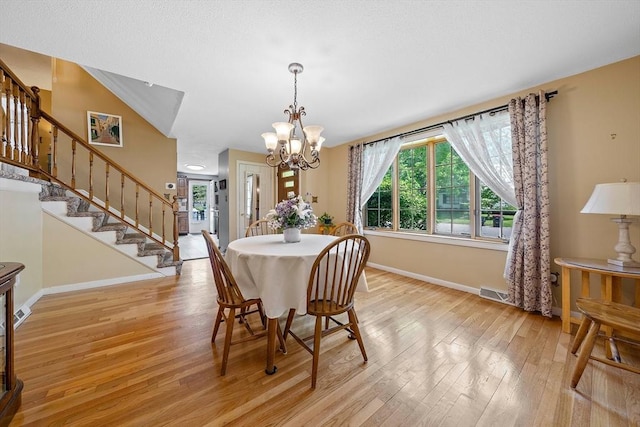 dining area featuring baseboards, light wood-style floors, a chandelier, and stairs