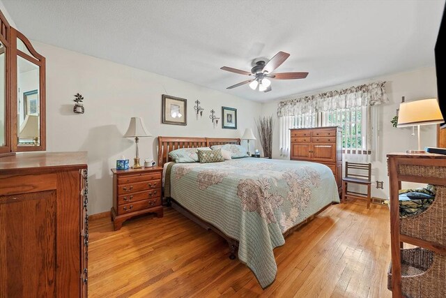 bedroom with light wood-style floors, baseboards, and a ceiling fan