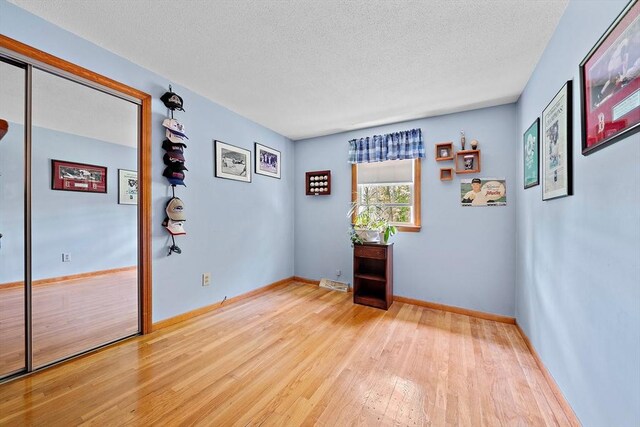 spare room with wood finished floors, a textured ceiling, and baseboards