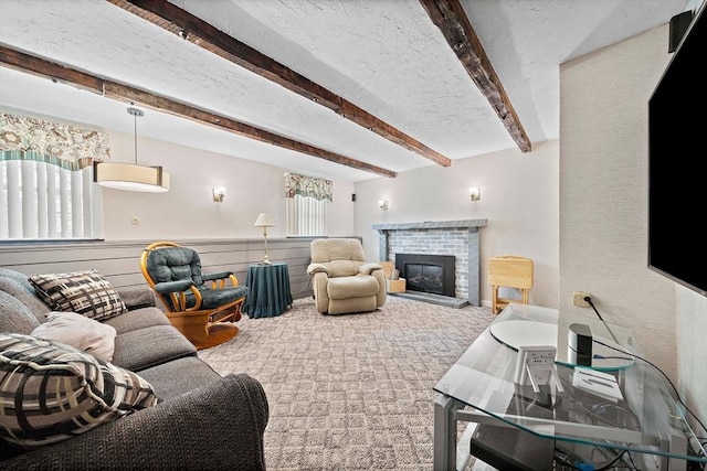 living area featuring beam ceiling, a fireplace, and carpet floors