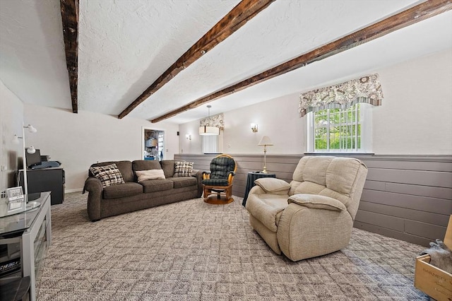 carpeted living room featuring wainscoting, beam ceiling, wood walls, and a textured ceiling