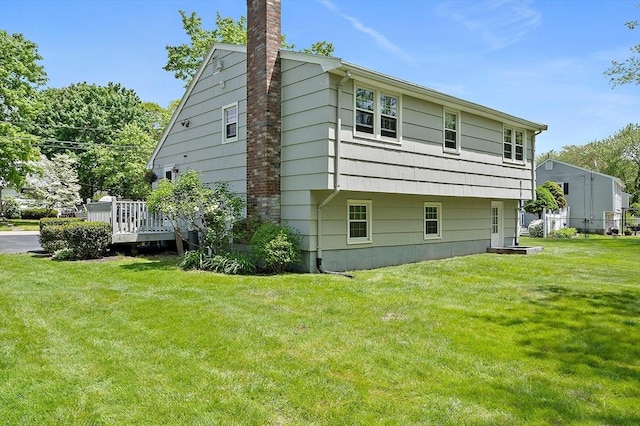 view of side of home with a chimney, a yard, and a deck