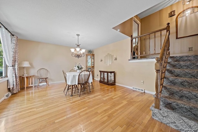 dining room featuring wood finished floors, stairs, a chandelier, and baseboards