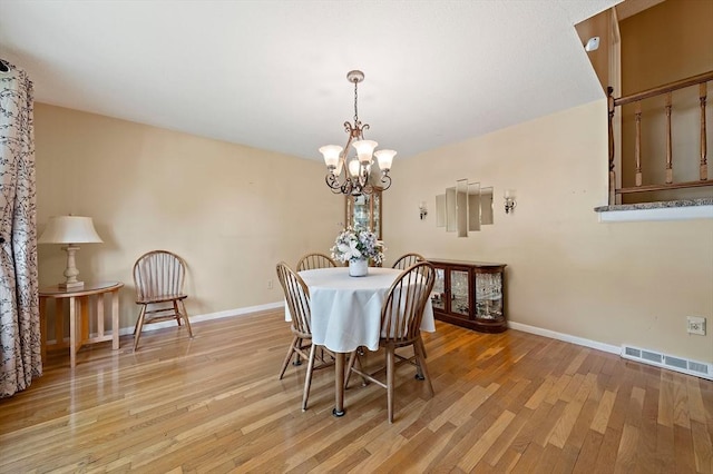 dining area featuring a chandelier, light wood-style flooring, and baseboards