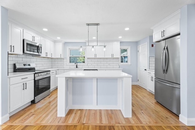 69 Kingman Ave, Revere, MA 02151 - kitchen featuring appliances with stainless steel finishes, a kitchen island, light countertops, light wood-style flooring, and decorative backsplash