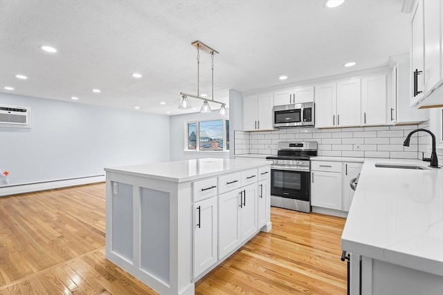 69 Kingman Ave, Revere, MA 02151 - kitchen with stainless steel appliances, light wood-style floors, a center island, backsplash, and a baseboard radiator