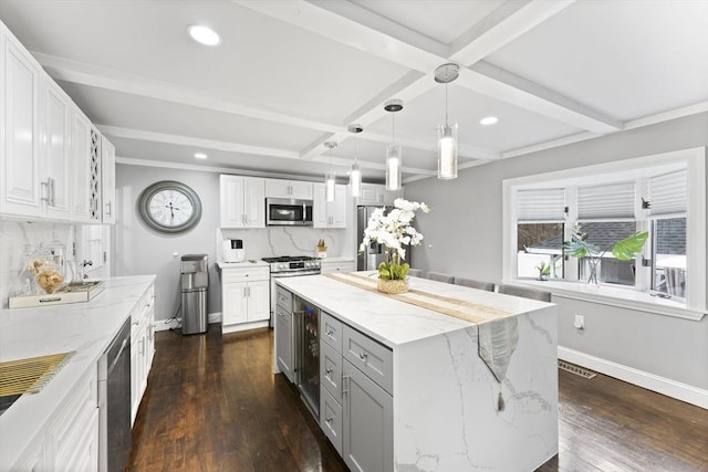 kitchen featuring beam ceiling, white cabinetry, stainless steel appliances, pendant lighting, and a kitchen island