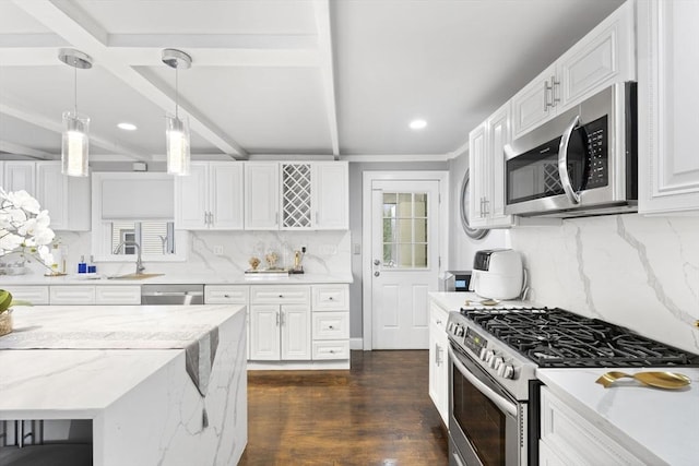 kitchen with appliances with stainless steel finishes, white cabinets, pendant lighting, beamed ceiling, and dark hardwood / wood-style floors