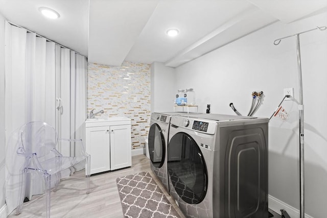 laundry room with cabinets, light hardwood / wood-style floors, and washing machine and clothes dryer