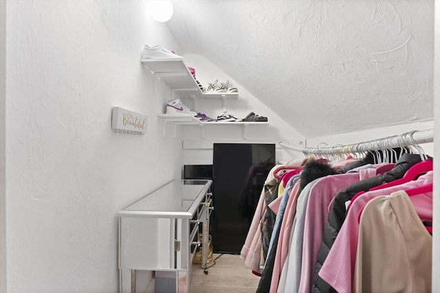 walk in closet featuring light wood-type flooring and lofted ceiling