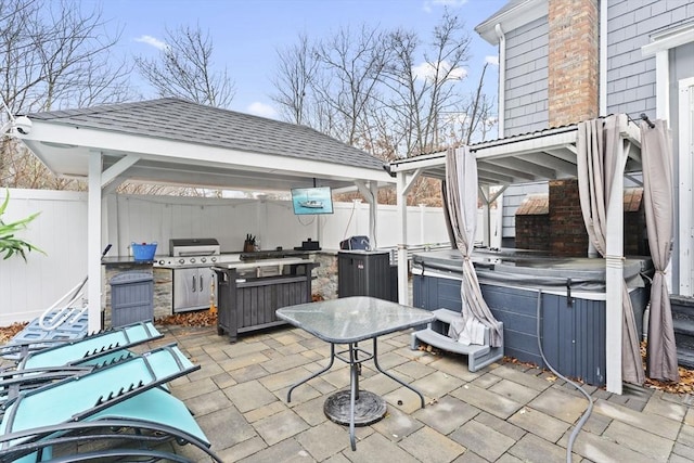 view of patio / terrace with a gazebo, a hot tub, grilling area, and exterior kitchen