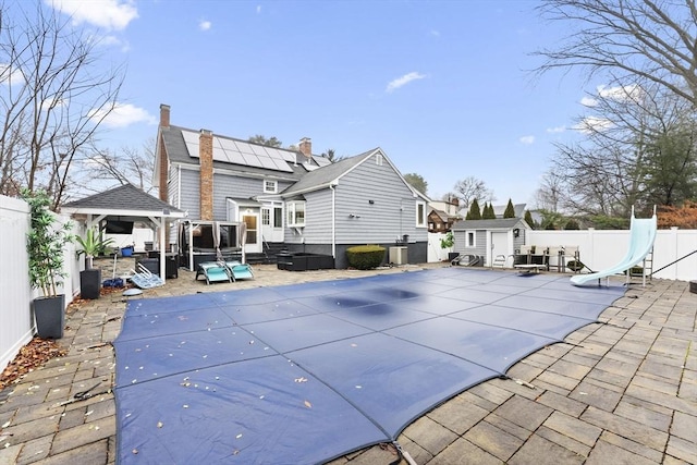 back of property featuring a shed, a covered pool, a patio area, and central air condition unit