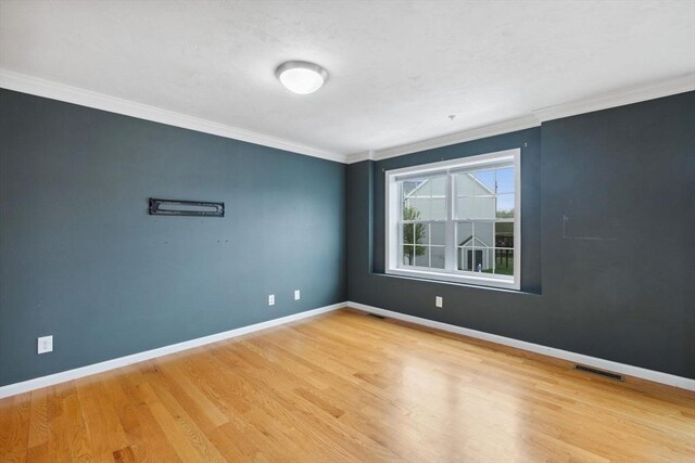 spare room with crown molding, wood finished floors, and baseboards