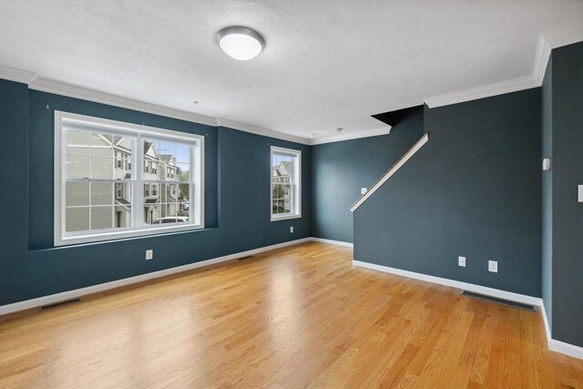 empty room featuring wood finished floors, crown molding, and baseboards