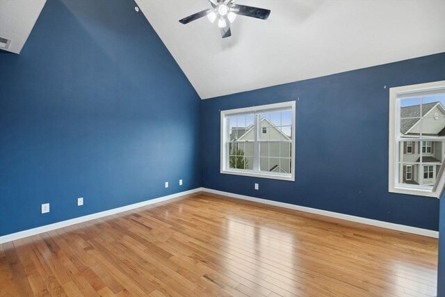 spare room with a ceiling fan, wood finished floors, lofted ceiling, and baseboards