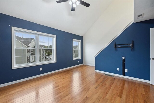 unfurnished living room with lofted ceiling, ceiling fan, wood finished floors, and baseboards