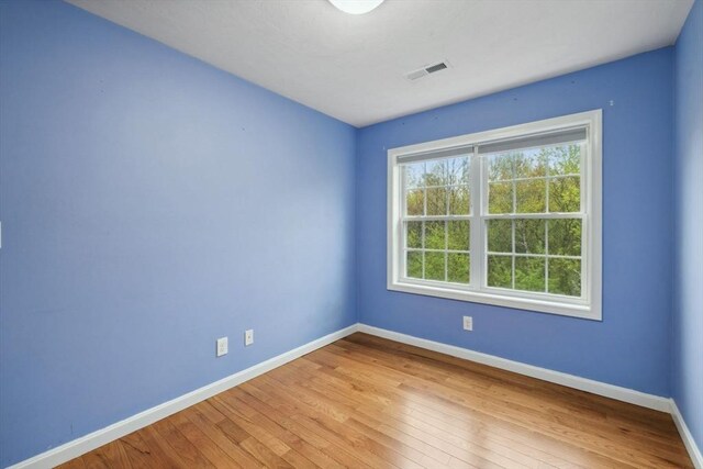 spare room with baseboards and hardwood / wood-style floors