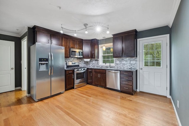 kitchen featuring appliances with stainless steel finishes, light wood-type flooring, dark brown cabinetry, tasteful backsplash, and crown molding
