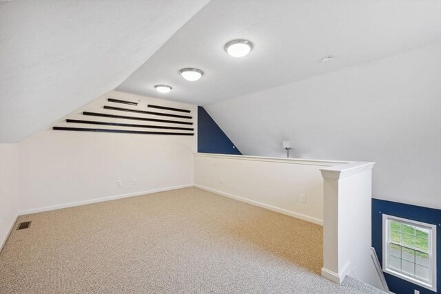 additional living space featuring carpet floors, lofted ceiling, and baseboards