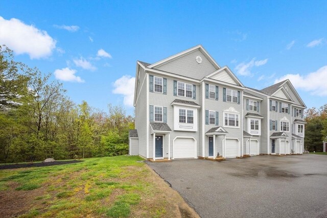 multi unit property with asphalt driveway, an attached garage, and a front lawn