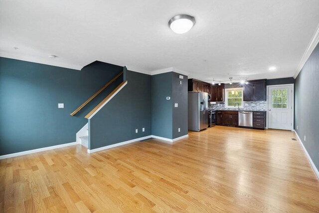 kitchen with stainless steel appliances, ornamental molding, light countertops, baseboards, and light wood-style floors