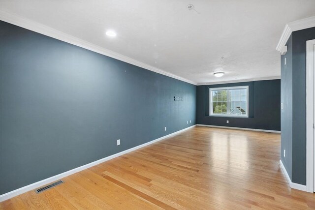 empty room featuring ornamental molding, light wood-style flooring, and baseboards