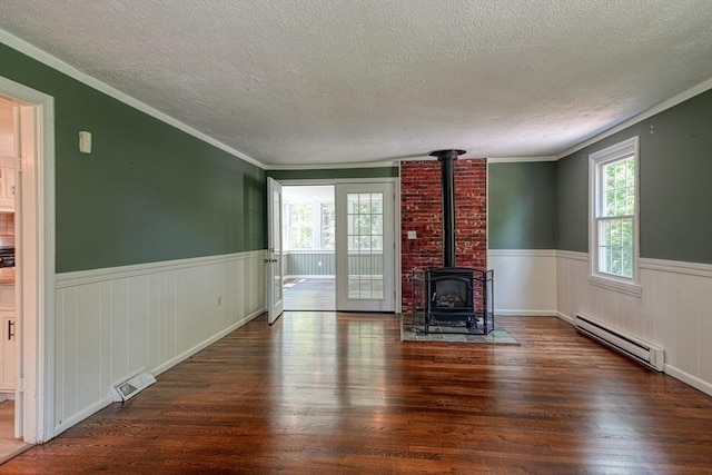 216 Davis St, Northborough, MA 01532 - unfurnished living room with a baseboard heating unit, a textured ceiling, wood finished floors, a wood stove, and a wainscoted wall