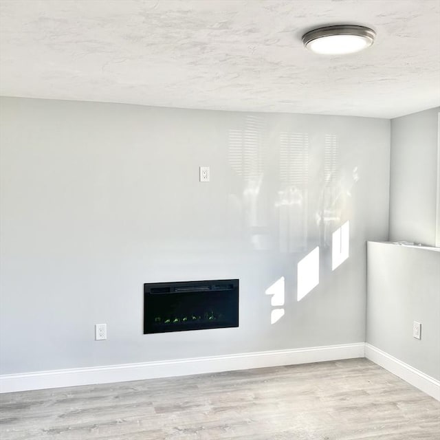 room details with a textured ceiling, wood finished floors, and baseboards