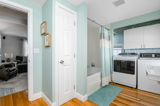 washroom with light hardwood / wood-style floors and washer and dryer