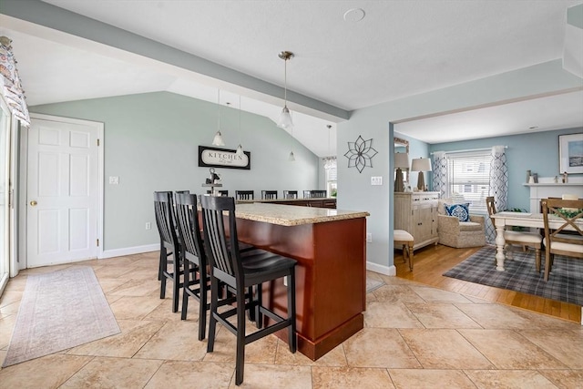 kitchen with hanging light fixtures, vaulted ceiling, and a kitchen bar