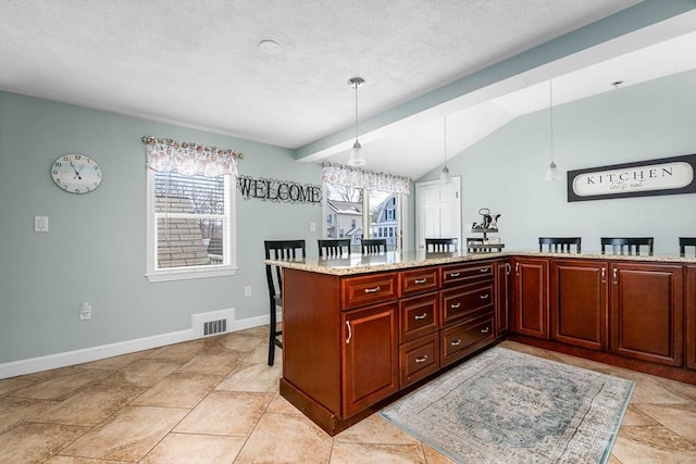 kitchen featuring lofted ceiling, a breakfast bar, decorative light fixtures, kitchen peninsula, and light stone countertops