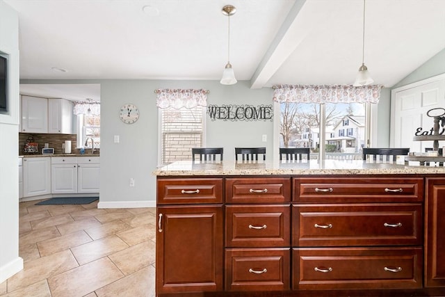 kitchen featuring plenty of natural light, sink, backsplash, and decorative light fixtures