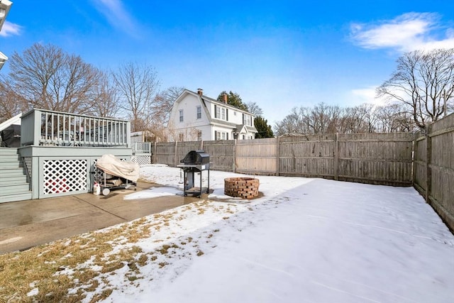 yard covered in snow with an outdoor fire pit and a deck