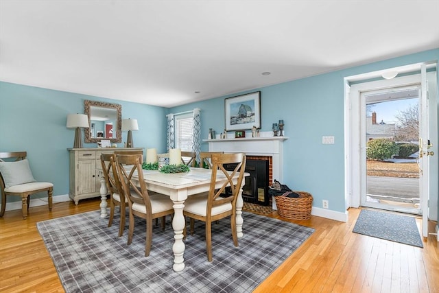 dining area featuring a brick fireplace and light wood-type flooring