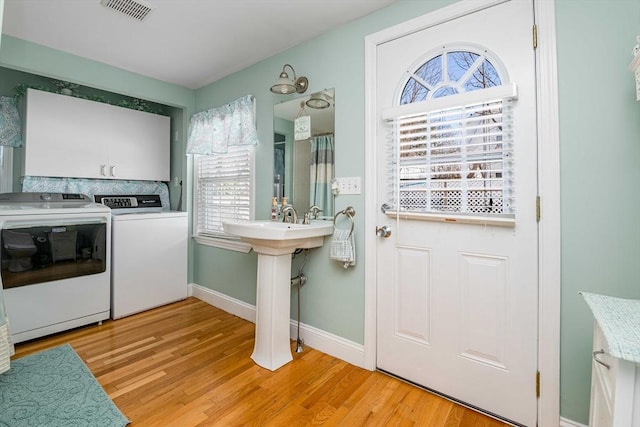 laundry area with washing machine and clothes dryer and light hardwood / wood-style flooring