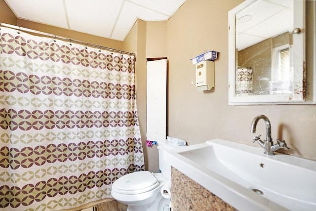 full bath with a shower with curtain, a paneled ceiling, toilet, and vanity