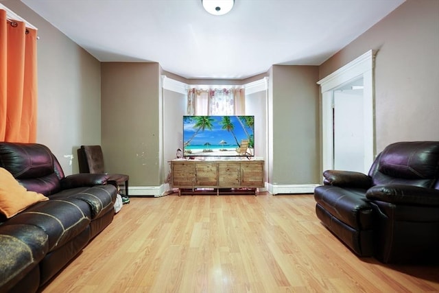 living area featuring a baseboard heating unit, baseboards, and light wood finished floors