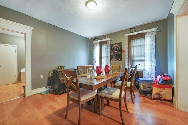 dining room with light wood-style flooring and a textured ceiling