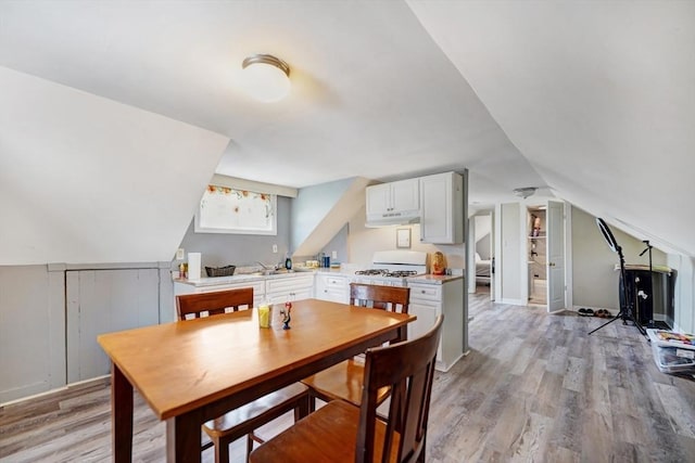 dining area featuring lofted ceiling and light wood-style floors