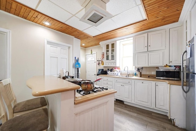 kitchen with white cabinetry, wooden ceiling, appliances with stainless steel finishes, and a sink