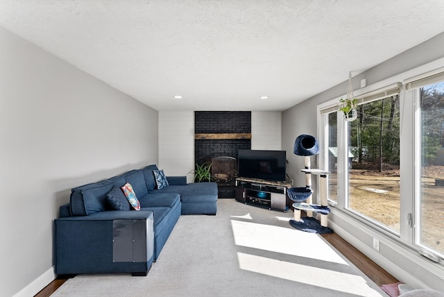 living area featuring a healthy amount of sunlight, a brick fireplace, a textured ceiling, and baseboards