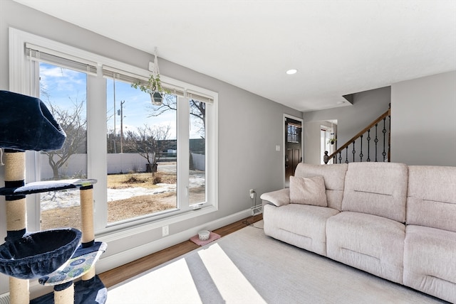 living area with stairs, plenty of natural light, wood finished floors, and baseboards