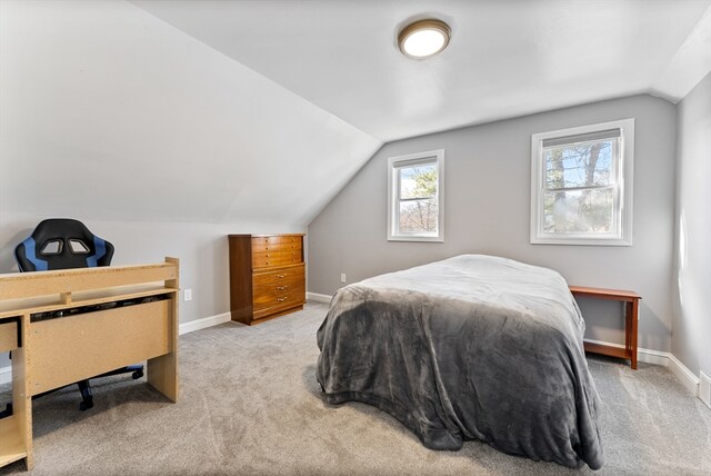 carpeted bedroom with lofted ceiling and baseboards