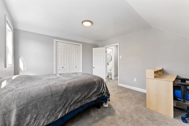 carpeted bedroom featuring a closet, baseboards, ensuite bath, and vaulted ceiling