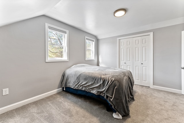 carpeted bedroom featuring a closet, baseboards, and vaulted ceiling