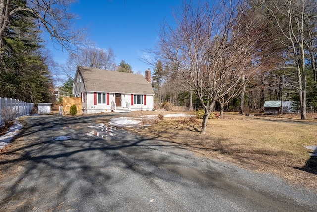 view of front of property with fence, driveway, and a chimney